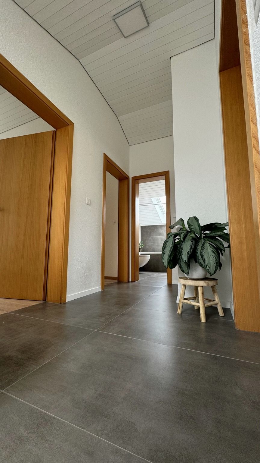 Couloir intérieur rénové, portes à encadrement en bois et sol en grand format gris
