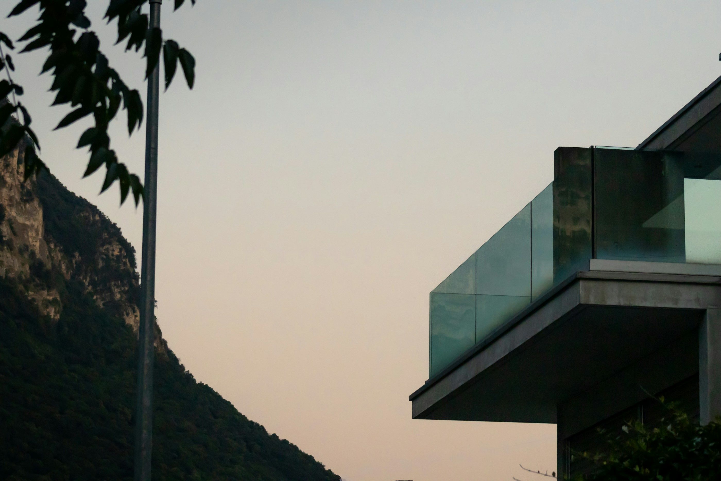 Maison contemporaine au balcon vitré, face aux montagnes du Tessin au crépuscule