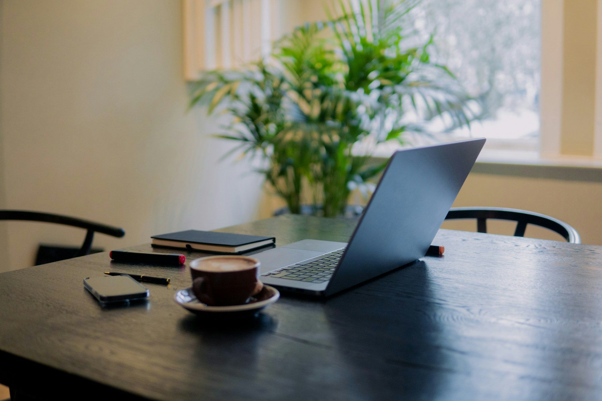 Ordinateur portable, carnet et tasse de café sur une table en bois sombre